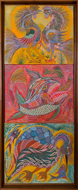 Three paintings stacked in a tall wooden box frame: two roosters beak to beak, a fish with gaping jaws and a heron with a fish. Fantastic Animals, Chico da Silva by Babá, 2003–2008, acrylic on canvas.